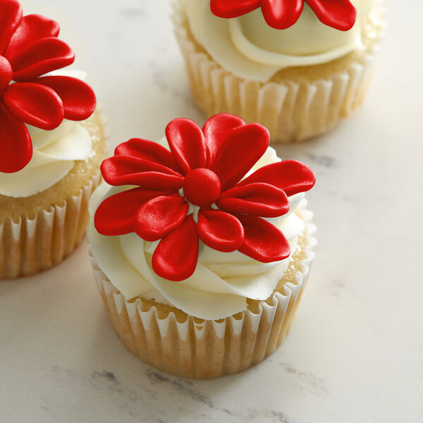 Three cupcakes with Satin Ice ChocoPan red modeling chocolate flowers on top.