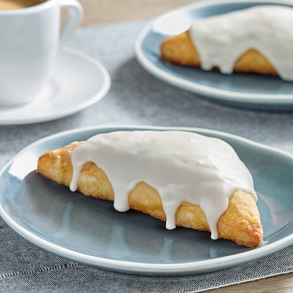 A pastry with white frosting on a plate.