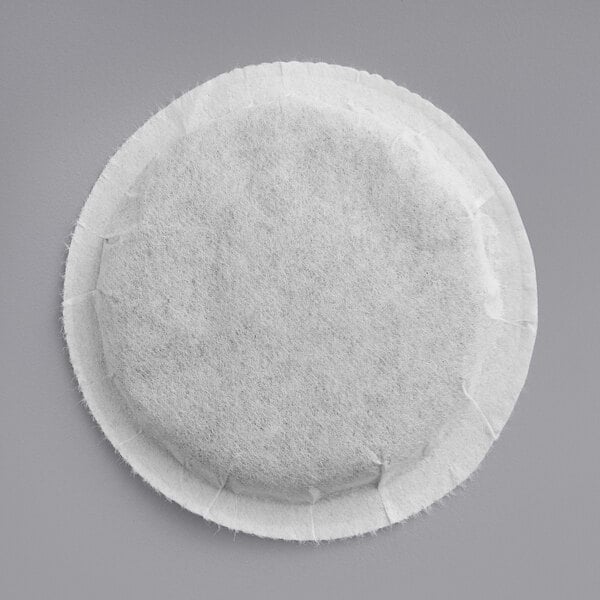 A white round Bigelow English Breakfast tea pod on a gray surface.