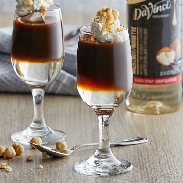 A close-up of a glass of brown liquid with DaVinci Gourmet Classic Hazelnut Flavoring Syrup.