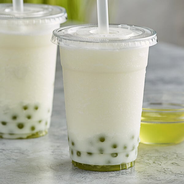 Two cups of banana bubble tea with straws.