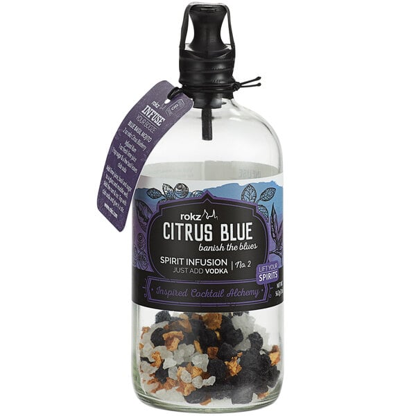 A close up of a Rokz Citrus Blueberry cocktail infusion kit bottle on a table. The label shows citrus and blueberries.