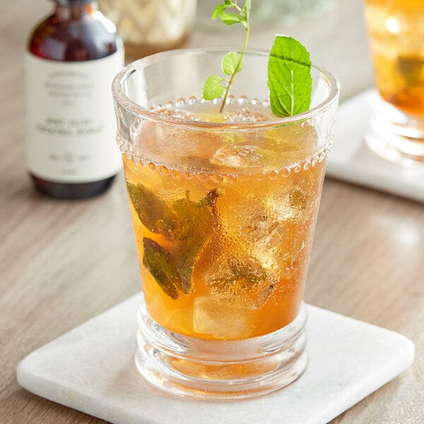 A glass of iced tea with a sprig of mint on top.
