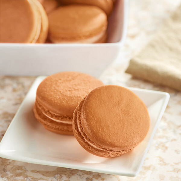A white plate of brown macarons.
