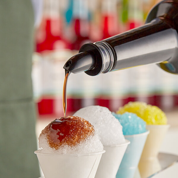 Hawaiian Shaved Ice Root Beer syrup being poured over a snow cone.