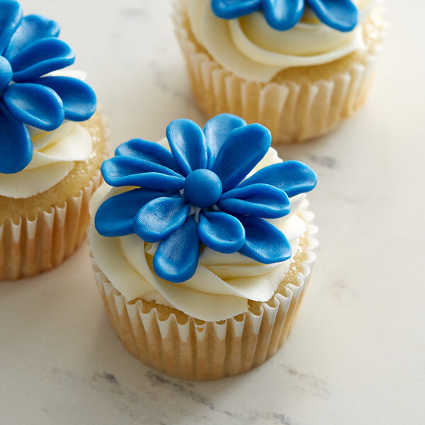 Three cupcakes with Satin Ice ChocoPan blue flowers on top.