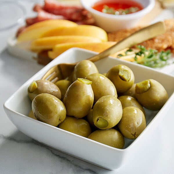 A bowl of Belosa Dill Pickle Stuffed Queen Olives on a table with other food.