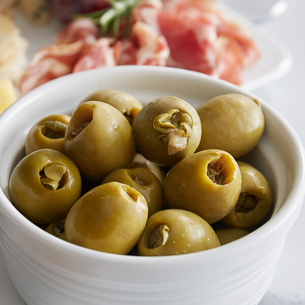 A bowl of Belosa caper stuffed green olives on a table in a deli.