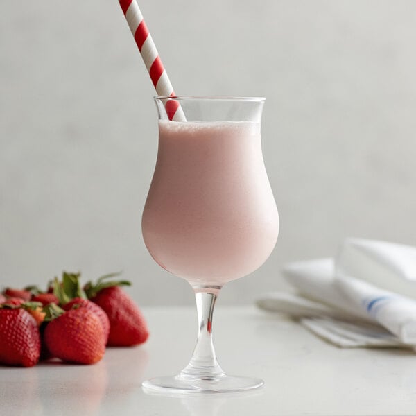 A glass of Monin strawberry smoothie with a straw on a white background.