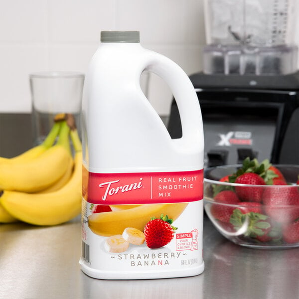 A white plastic container of Torani Strawberry Banana Smoothie Mix with a red label.