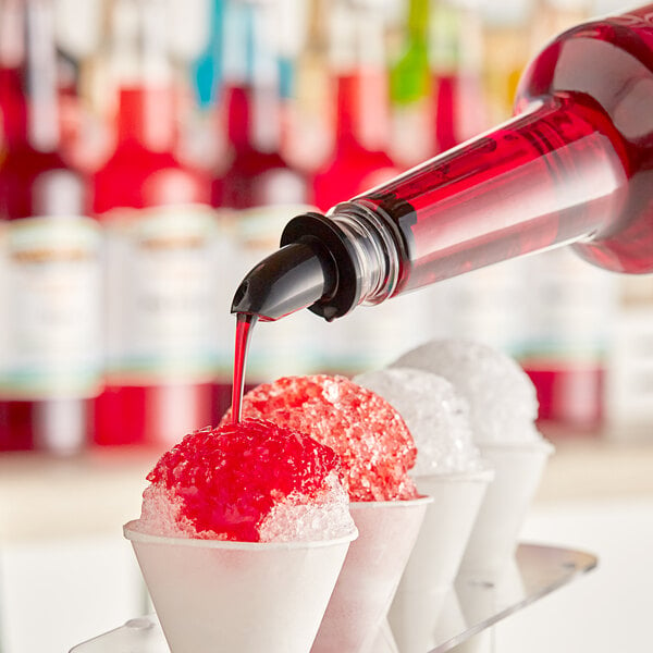 A person pouring Hawaiian Shaved Ice Tiger's Blood syrup onto a cone of shaved ice.