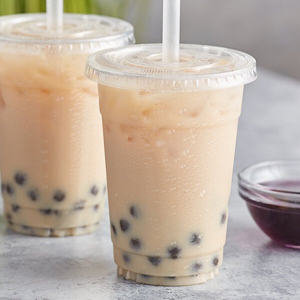 Two plastic cups of lavender bubble tea with straws and black balls.