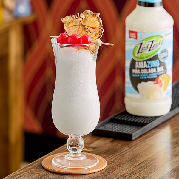 A glass of Zing Zang Pina Colada Mix with a cherry and pineapple garnish.