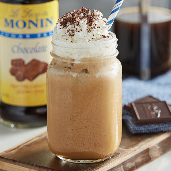 A glass of brown liquid with whipped cream and chocolate syrup on top.