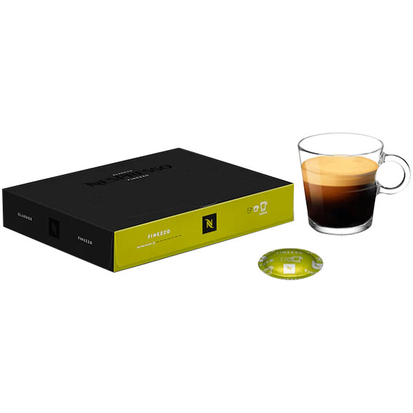 A black box of Nespresso Professional Finezzo coffee capsules on a table next to a glass of coffee.