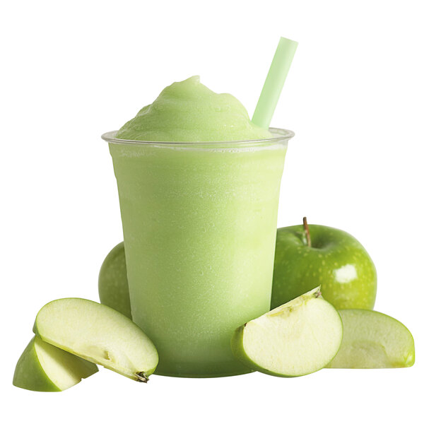 A green smoothie with a straw and apple slices.