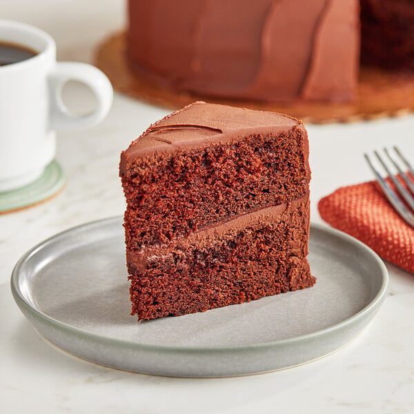 A slice of chocolate cake on a plate next to a cup of coffee.