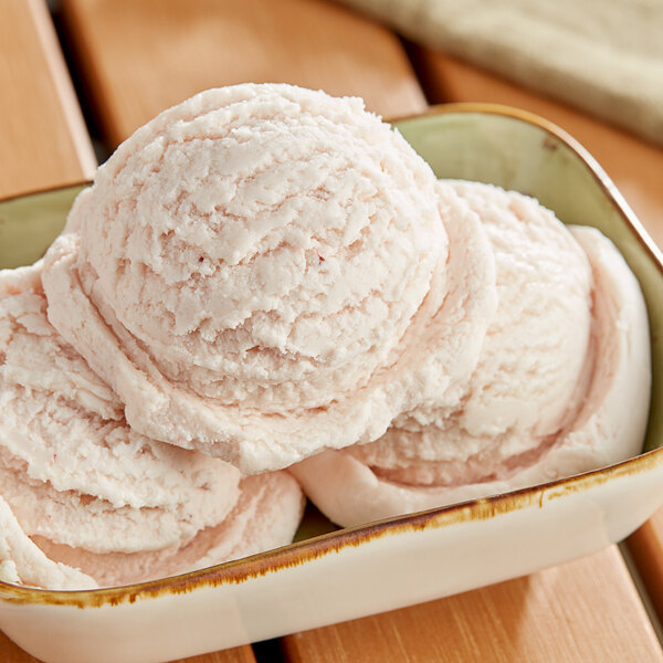 A bowl of I. Rice strawberry hard serve ice cream with a scoop on top.