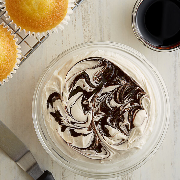 A bowl of yellow frosting with a cupcake on top.