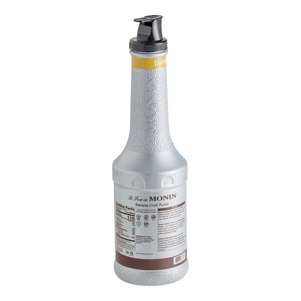 A close-up of a white Monin Banana Fruit Puree bottle with a yellow cap.
