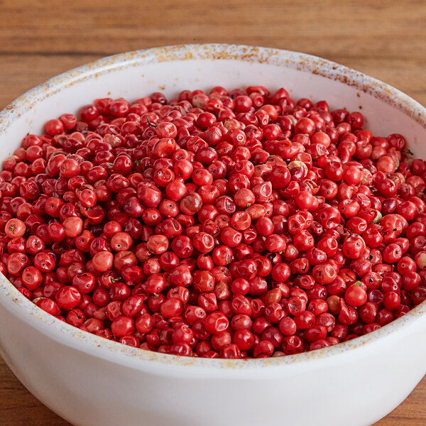 A bowl of Regal Pink Peppercorns on a wooden table.