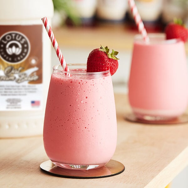 A glass of pink Lotus Plant Energy drink with a straw and a strawberry.