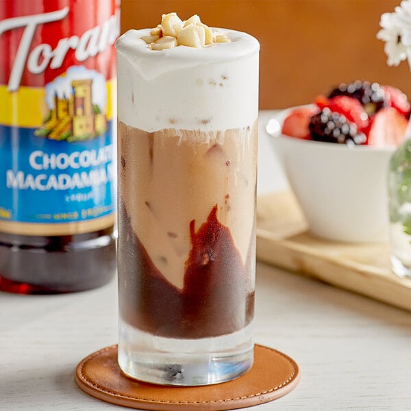 A glass of ice cream with Torani Chocolate Macadamia Nut syrup and chocolate topping.