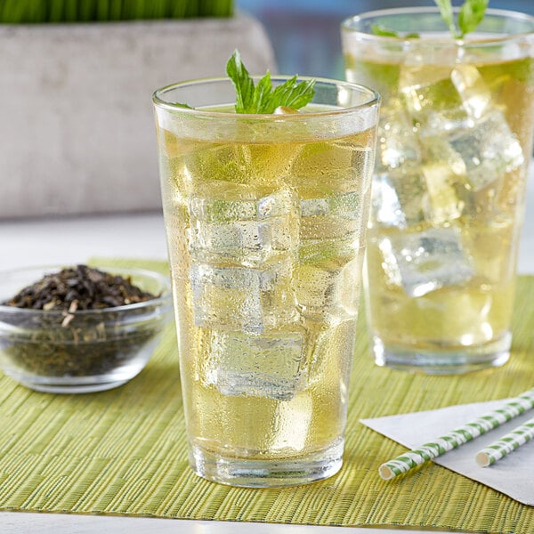 A glass of Bossen jasmine green loose leaf tea with ice and a mint leaf on top.