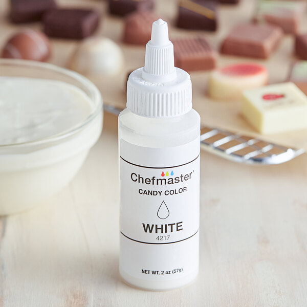 A white bottle of Chefmaster white oil-based candy color with a white cap next to a bowl of white liquid.