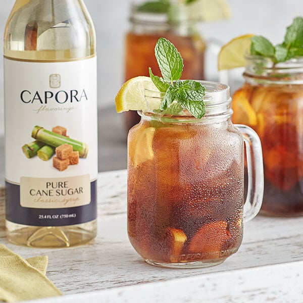 A glass jar of brown Capora Cane Sugar Sweetener syrup with a straw in it.