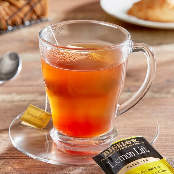 A glass cup of Bigelow Lemon Lift tea with a tea bag in it.