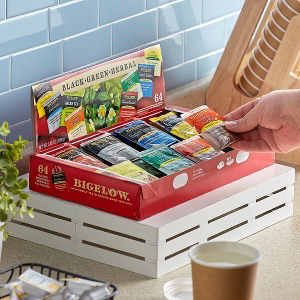 A hand holding a Bigelow Tea variety tray box.