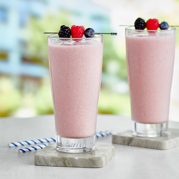 Two glasses of Capora mixed berry smoothies with berries on top.