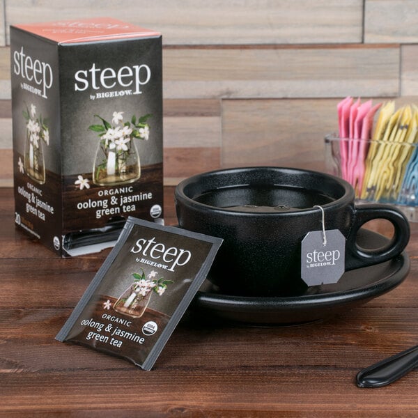 A cup of tea made with Steep By Bigelow Organic Oolong and Jasmine Green Tea next to a box of tea bags.