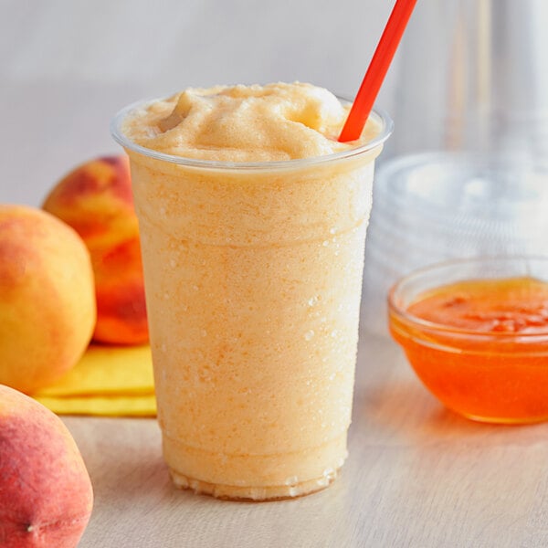 A cup of orange smoothie with a straw and a bowl of Bossen Peach Jam.
