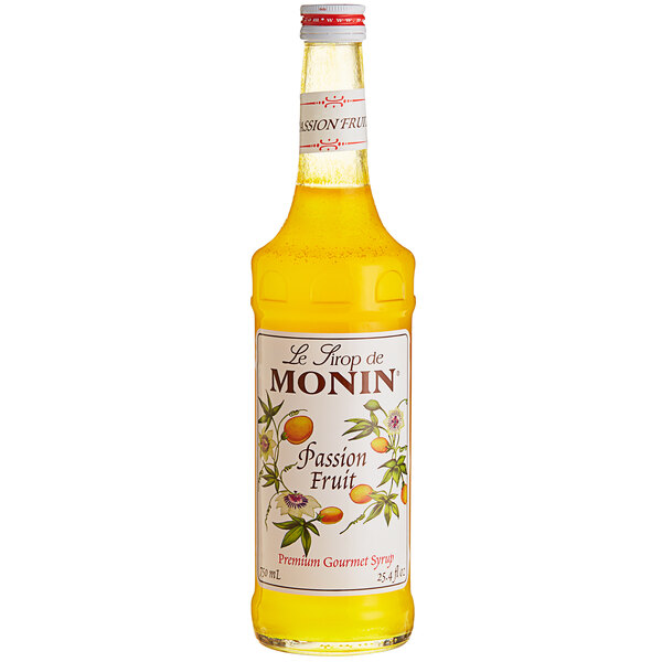 A bottle of Monin Passion Fruit Syrup with yellow liquid.
