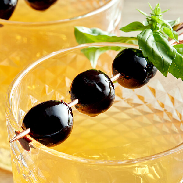 Two glasses of drinks garnished with Luxardo Maraschino Cherries on a table in a cocktail bar.