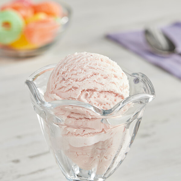 A bowl of strawberry ice cream with a scoop on top.