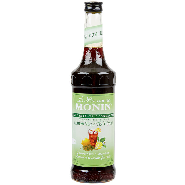 A close up of a Monin Lemon Tea Concentrate bottle with a green label.