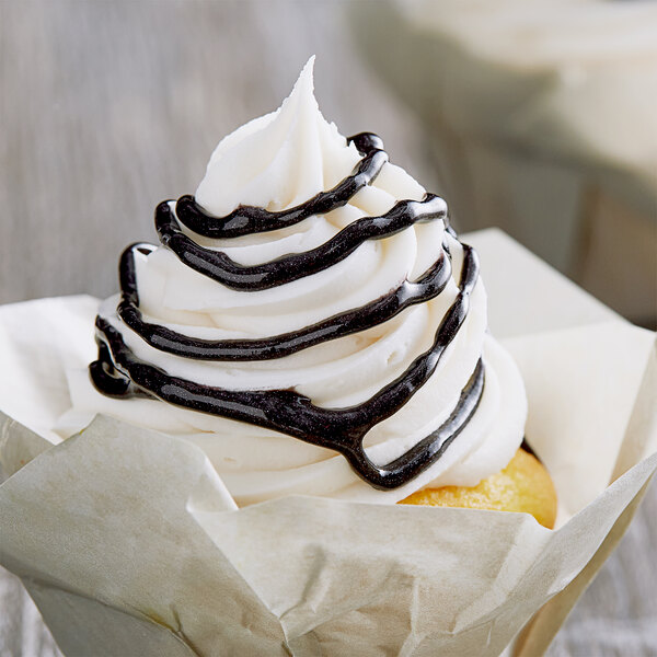 A close up of a cupcake with white frosting and black swirls.