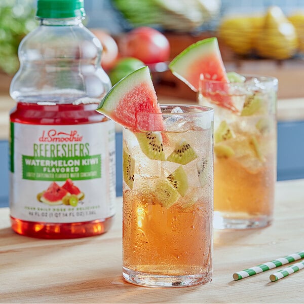 A glass of Dr. Smoothie Watermelon Kiwi Refresher with kiwi slices and ice on a table.