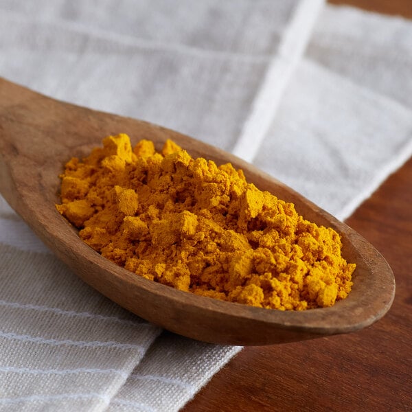 A spoon filled with Regal Ground Turmeric on a white cloth.