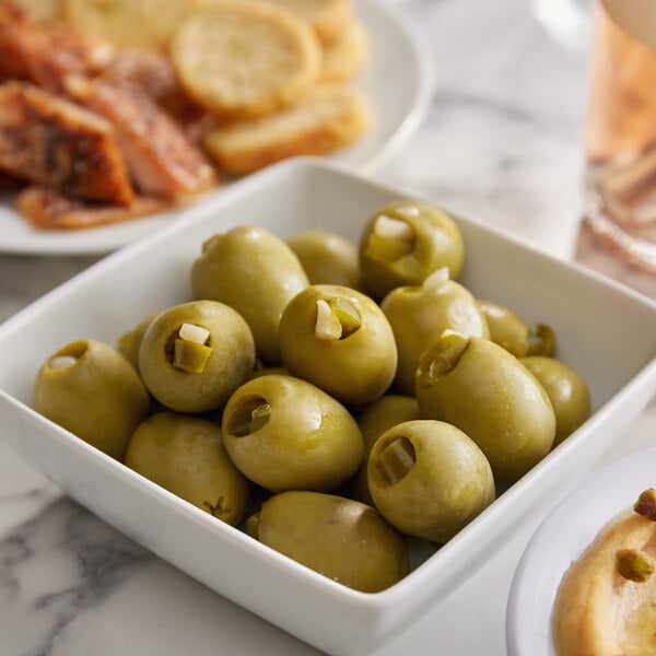 A bowl of green olives on a table.