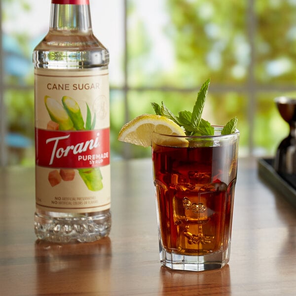 A glass of iced tea next to a bottle of Torani Pure Cane Sugar syrup.