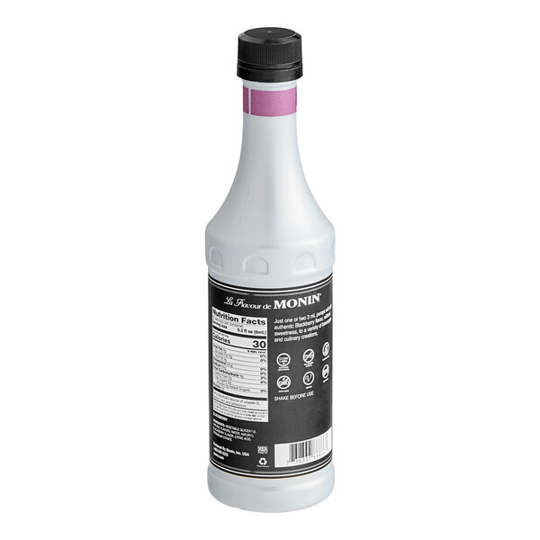 A white Monin bottle with black labels filled with purple liquid.