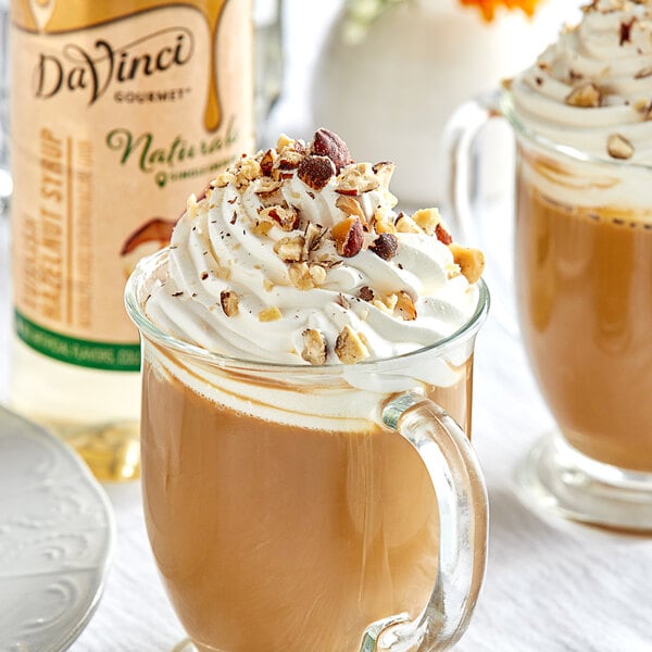 A glass mug of DaVinci Gourmet Turkish Hazelnut syrup coffee with whipped cream and nuts.