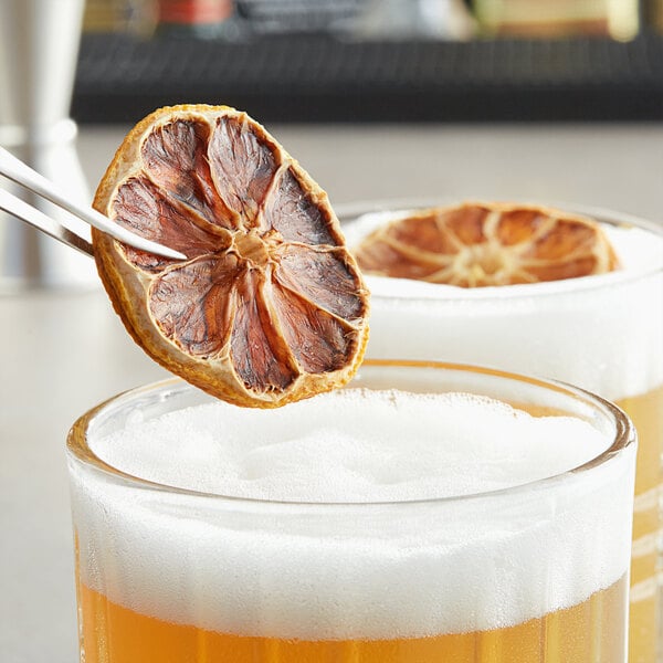 A close-up of a glass with a Blue Henry dried lemon slice on the rim.