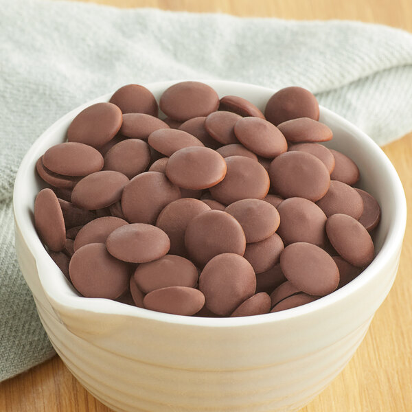 A bowl of Callebaut dark chocolate chips on a wooden table.