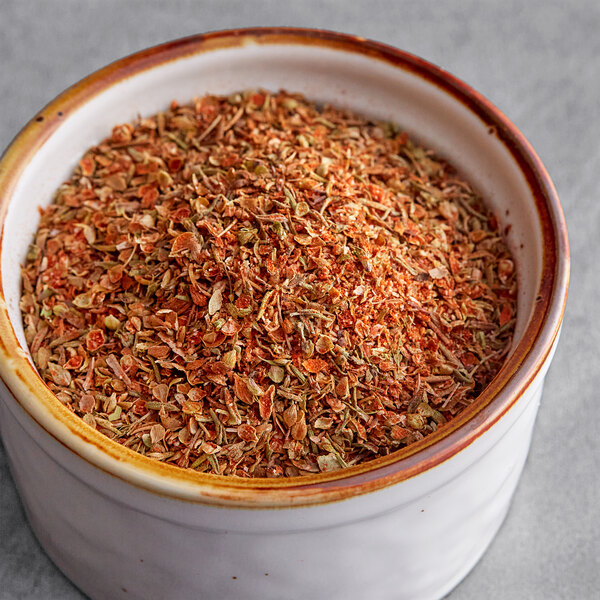 A bowl of Regal Creole Seasoning on a counter with seasoned ground meat.