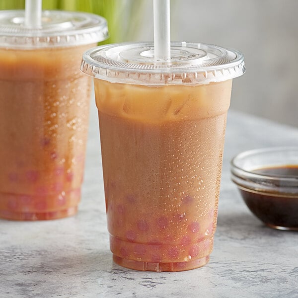 Two plastic cups of brown ginger bubble tea on a table.